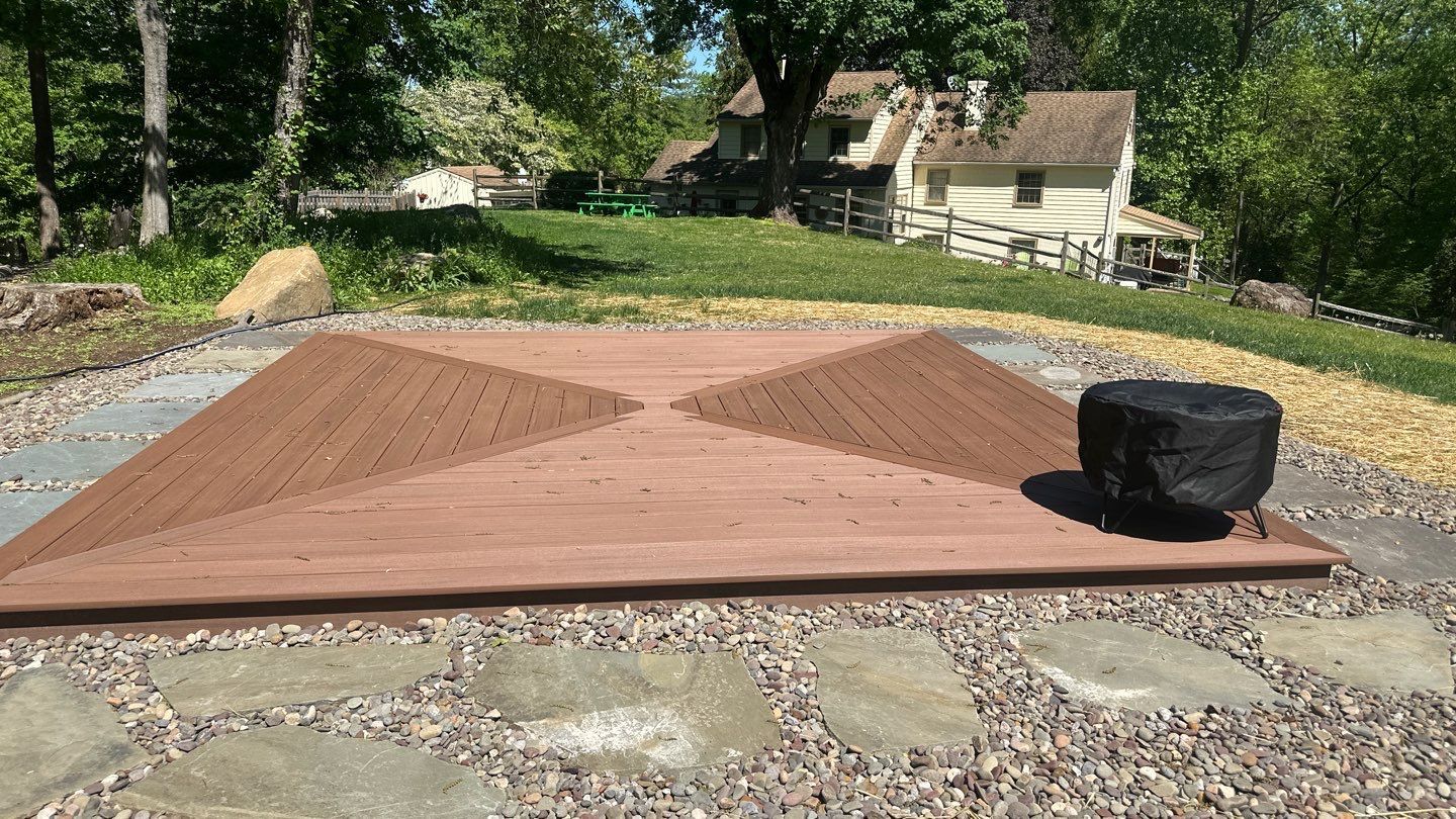 Reddish-brown composite deck with decorative sunburst board pattern on a flagstone patio in Chester County PA